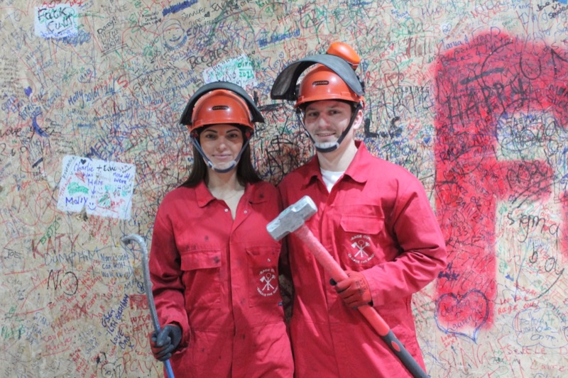 Two customers in red overalls with a sledgehammer and crowbar in a Rage Out rage room